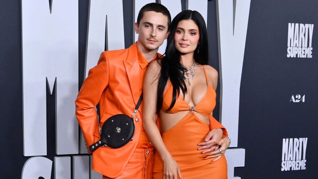 Timothée Chalamet i Kylie Jenner uskladili su se u custom Chrome Hearts izdanjima za svoje drugo pojavljivanje na crvenom tepihu. U ponedeljak, 8. decembra, par se u stilu pojavio zajedno na crvenom tepihu. Chalamet (29) prisustvovao je premijeri svog najnovijeg filma, Marty Supreme, u Los Anđelesu, a Jenner mu se pridružila kao pratnja. Stigli su u usklađenim custom Chrome Hearts kombinacijama. Chalamet je nosio jarko narandžasto kožno odelo, uz svilenu košulju i čizme u istoj nijansi. Preko ramena mu je visila i crna kožna futrola za stoni tenis Chrome Hearts. Osnivačica Kylie Cosmetics, 28, nosila je dugačku narandžastu haljinu sa trouglastim isečcima ispod grudi i na struku. Dno izrazito dubokog V-izreza bilo je ukrašeno krstom, motivom koji se ponavljao i na njenoj ogrlici, sa više krstova različite veličine. Stajling je upotpunila narandžastim špicastim salonkama. Jenner je narandžastu provukla kroz ceo look—nokti su joj bili jarko narandžasti, a rumenilo u toplim narandžastim tonovima. U makeup-u su se blendali roze i narandžasti detalji, dok je na usnama imala mat nude nijansu. Kosu je nosila isfeniranu ravno i jednostavno. Iako su u vezi od proleća 2023, ovo je tek drugi put da Jenner prati glumca na crvenom tepihu. U maju su zajedno debitovali na crvenom tepihu u Rimu, na 70. David Di Donatello nagradama, gde je Chalamet, zvezda filma A Complete Unknown, dobio nagradu za kinematografsko dostignuće. Kao i ovog ponedeljka, i tada su nosili usklađene kombinacije. Chalamet je izabrao elegantno baršunasto odelo sa boutonnière detaljem, dok je Jenner nosila pripijenu haljinu dubokog dekoltea iz Schiaparelli Fall/Winter 2025 kolekcije. Jenner je look upotpunila baršunastom clutch torbicom sa zlatnim vezom i upečatljivim Schiaparelli minđušama—jedna u obliku zlatnog mesinganog prsta sa biserom i kristalom, a druga u obliku skulpturirane ruke sa kristalnim noktom i bisernim privezakom. Kosu je podigla u zalizanu punđu da bi se nakit istakao. Daleko pre svog debija na crvenom tepihu, Jenner je Chalameta pratila na Golden Globes, BAFTA nagradama i Oscarima—na svim događajima gde je bio nominovan za ulogu Boba Dylana u biografskom filmu A Complete Unknown. Na Zlatnim globusima 2025. Jenner je zablistala u srebrnoj haljini od lančica, otvorenih leđa. Nosila je crnu kosu u talasima i nakit Lorraine Schwartz. Chalamet je tada nosio crno odelo uz sivu košulju i plavi šal. Mesec dana kasnije, na BAFTA nagradama, ona se pojavila u elegantnoj crnoj haljini sa svetlucavim detaljima, dok je Chalamet nosio klasično crno Bottega Veneta odelo uz crnu majicu i cipele, uz Cartier nakit. Na Oscarima, Chalamet je nosio custom Givenchy odelo u nijansi puter žute. Jenner je nosila Miu Miu haljinu s otvorenim detaljima i bogatom aplikacijom perlica, koju je uparila sa svojim prepoznatljivim Lorraine Schwartz nakitom. Film Marty Supreme u bioskope stiže 25. decembra.